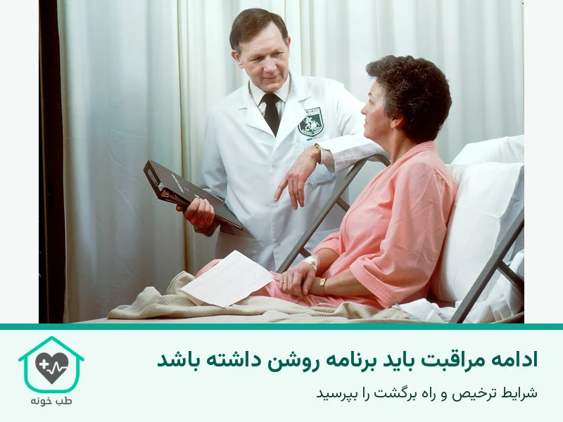پزشک در حال مرور برگه و گفتوگو با زن کنار تخت بیمارستان